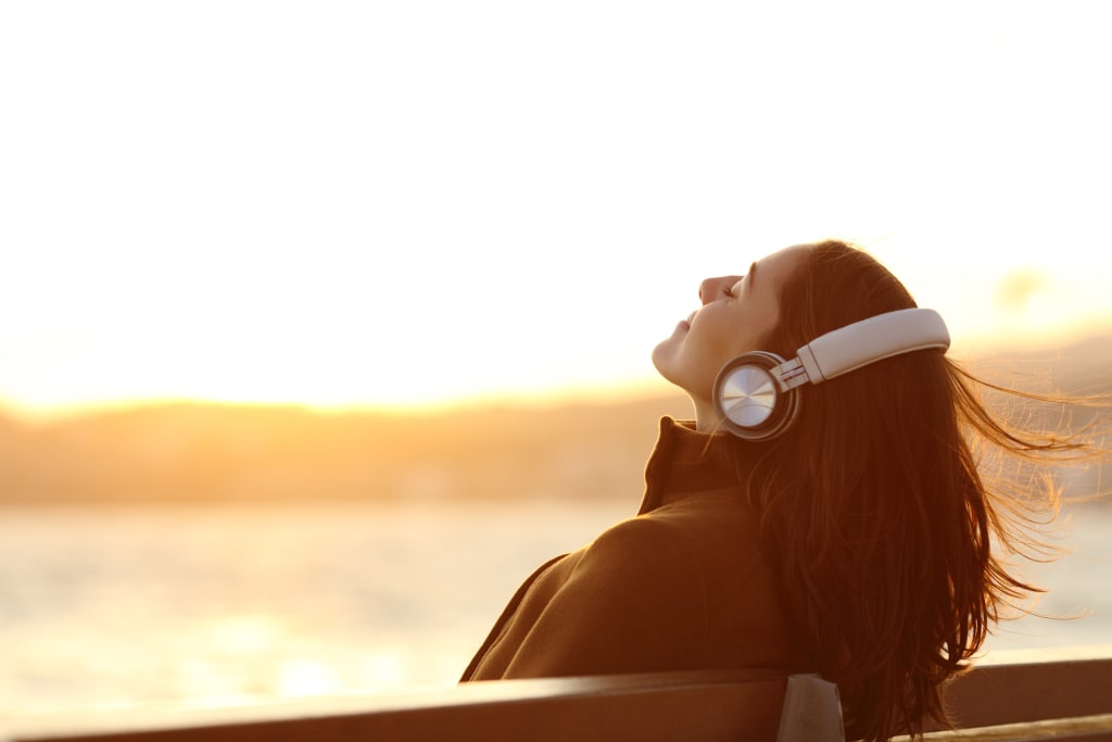 Woman with headphones breathing on a bench in winter